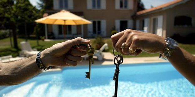 Remise des clés devant une maison avec piscine lors d'un échange de maison