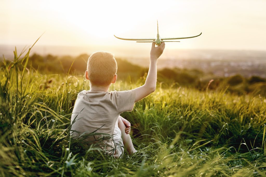 Petit garçon assis dans l'herbe avec un avion en jouet