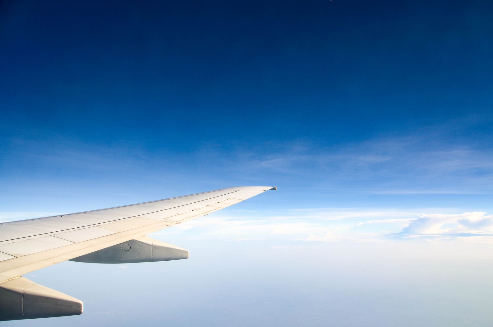 Airplane wing above the clouds representing summer 2026 airfare price hikes