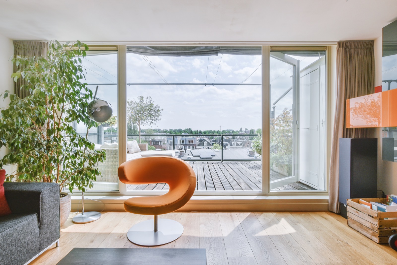 Séjour lumineux d’un appartement avec une grande baie vitrée ouvrant sur une terrasse et les toits de la ville
