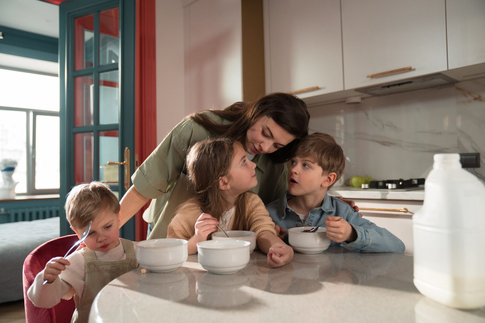 Une mère et ses trois enfants prennent le petit-déjeuner dans la cuisine d’une maison échangée